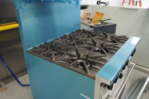 gas-fired 6 burner stove with gas fryer in background