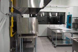 a kitchen with stainless steel tables and hood vent with gas-fired equipment